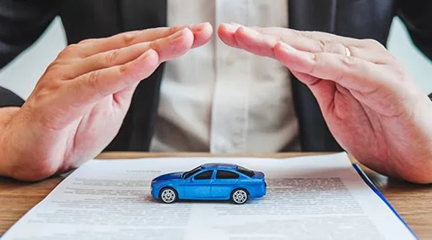 Hands sheltering a car, auto insurance protection